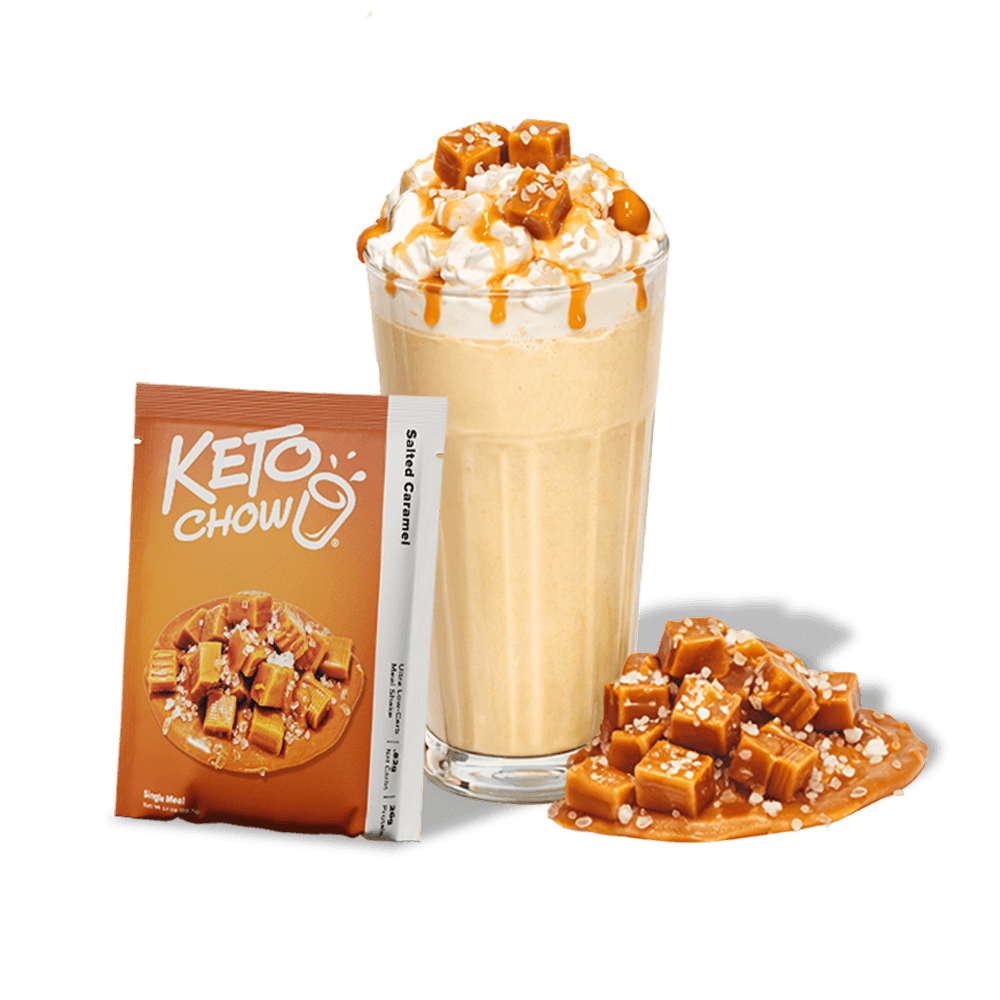 KETO CHOW Salted Caramel shake in a glass, with whipped cream and caramel cubes. Orange KETO CHOW Single Meal pouch and white Salted Caramel stick pack.