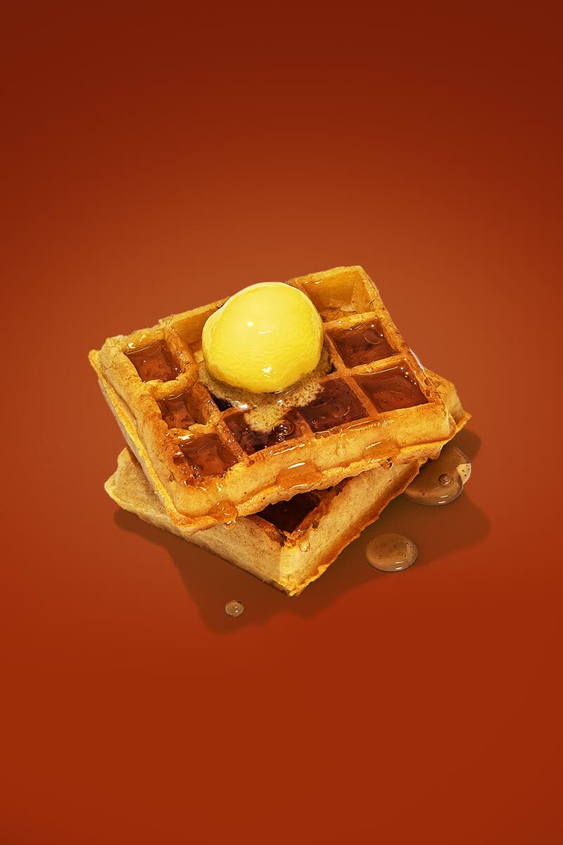 Two crisp waffles topped with a dollop of butter