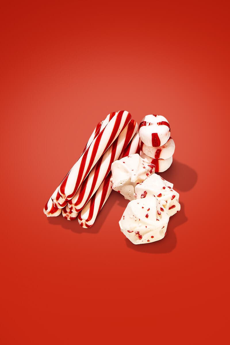 A small handful of short peppermint sticks, some peppermint mints, and some red-speckled peppermint macarons