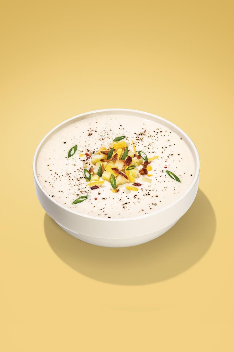 Creamy potato soup, garnished with green onions and bacon